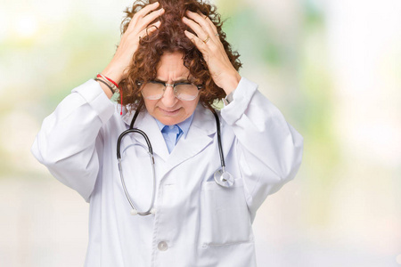 中年年龄更高的医生妇女，在孤立的背景下，患有头痛，绝望和压力，因为疼痛和偏头痛。手放在头上。