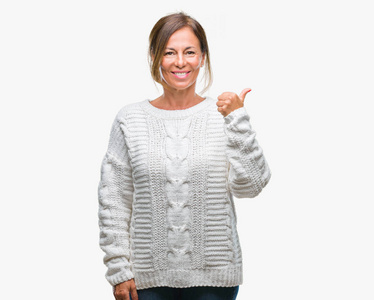 中年老年西班牙裔妇女穿着冬季毛衣，在孤立的背景下，用手做快乐的竖起大拇指的手势。赞许的表情看着相机，显示出成功。
