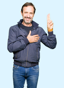 中年英俊男子穿着夹克,用手在胸前和手指上发誓,许下忠诚的誓言照片