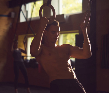 适合运动和运动运动员在健身房工作。 男子训练使用体操环。 体育竞技生活方式和健身理念。