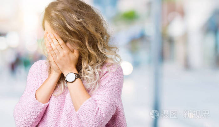 美丽的年轻金发女人在孤立的背景上,悲伤的表情覆盖着脸,双手哭泣.