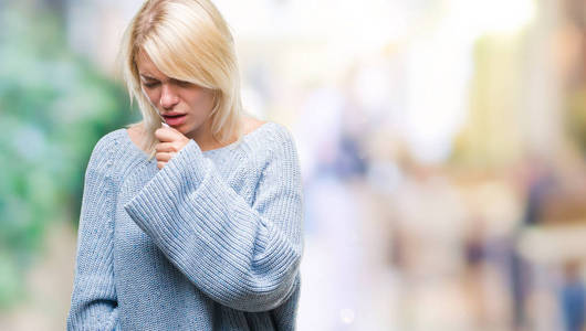 年轻漂亮的金发女人穿着冬季毛衣，在孤立的背景下感到不适，咳嗽是感冒或支气管炎的症状。 医疗保健概念。