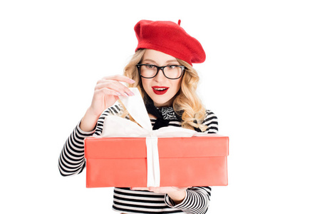 戴着眼镜的金发女郎看着礼品盒，礼品盒上有白色的丝带