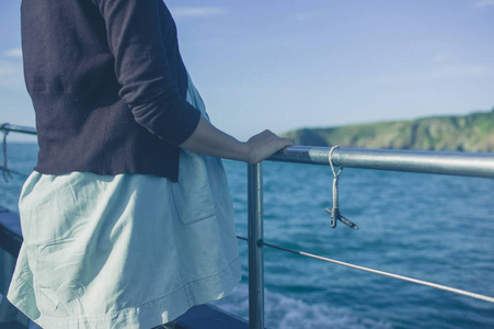 夏天，一个年轻的女人站在船上的栏杆旁