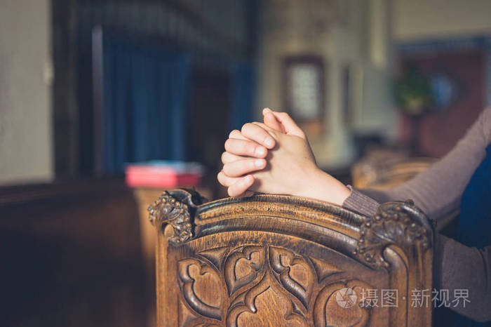 在教堂里祈祷的女人双手合拢
