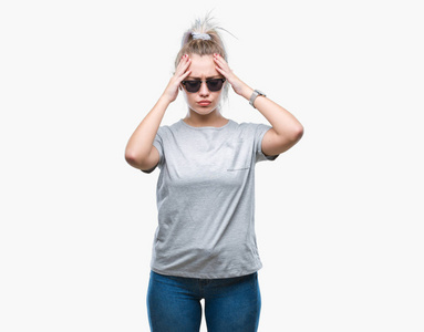 年轻的金发女人戴着太阳镜，在孤立的背景下，因为疼痛和偏头痛而感到头痛绝望和压力。 手放在头上。