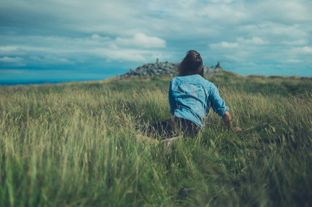 一个年轻女子躺在山顶的田野里