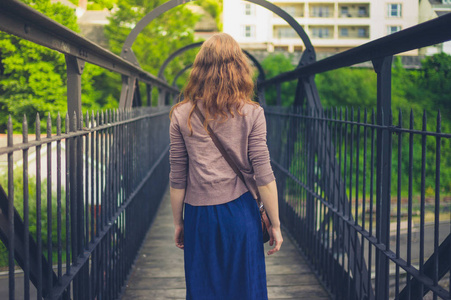 夏天，一位年轻女子正走在外面的一座钢桥上