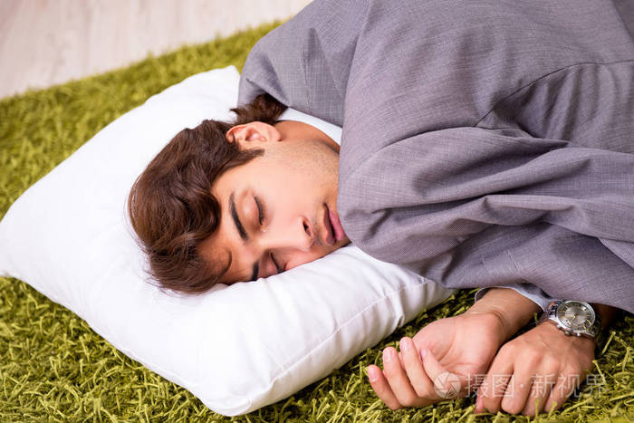 在办公室地板上睡觉的年轻员工