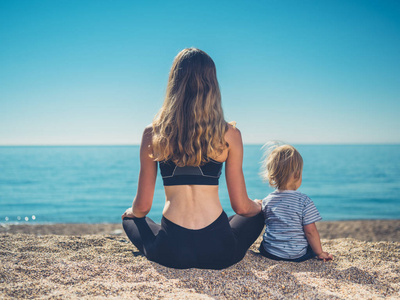 一位穿着健身服的年轻母亲带着她的孩子在海滩上放松