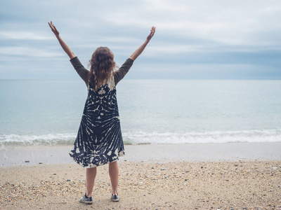 一位年轻女子正在海边的海滩上举起双臂