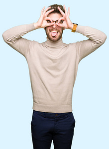 年轻英俊的商人戴着眼镜做着好的手势，就像双筒望远镜伸出舌头，透过手指看着眼睛。 疯狂的表情。