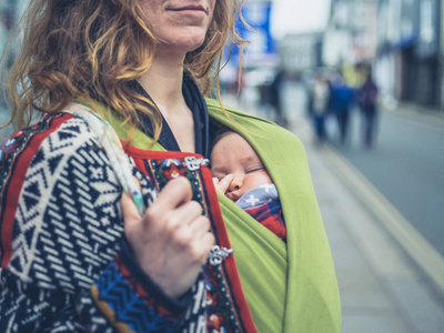 街上一位年轻的母亲，带着婴儿用吊带