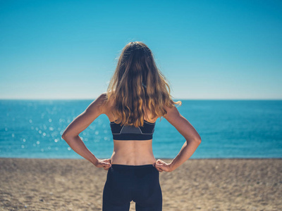 夏天，一位身材匀称的年轻女子站在海滩上