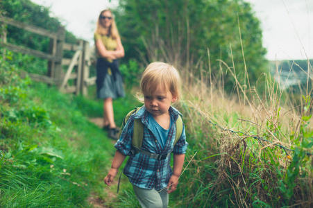 一个小蹒跚学步的孩子正和他的母亲在乡下散步