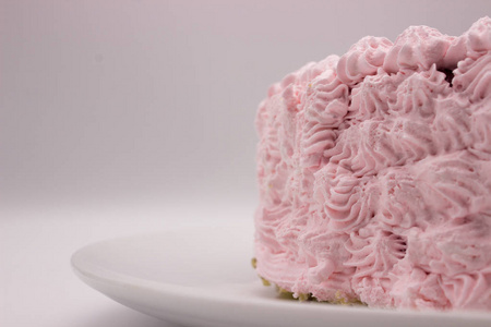 白色灰色背景的盘子上的奶油粉红色蛋糕。 具有复制空间区域的图像。