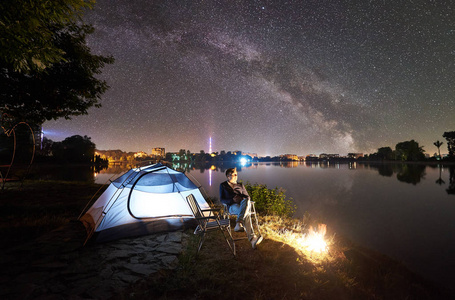 在篝火旁的湖岸上休息，欣赏美丽的夜空，满是星星和银河