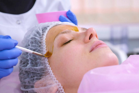 美容师用刷子把女人脸上的化学剥皮。清洁面部皮肤, 减轻雀斑皮肤