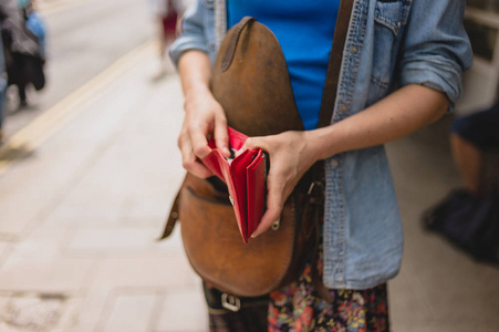 一位年轻女子站在街上，正打开钱包买东西
