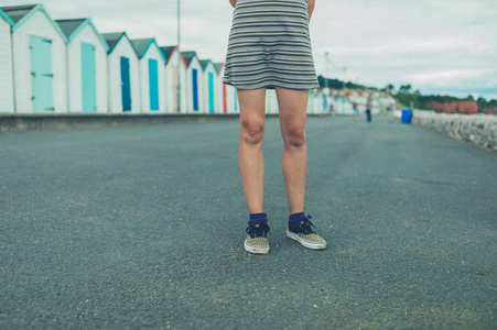 夏天，一个年轻的女人站在海滩小屋旁边