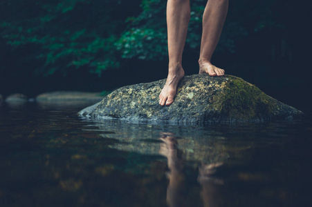 一个年轻女子赤脚站在河里的岩石上的脚