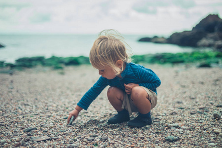 一个小孩正在沙滩上玩石头