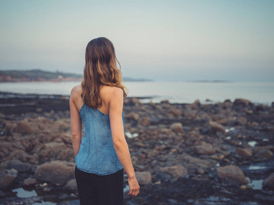 日落时分，一位年轻女子站在海岸上