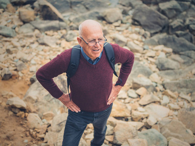 一个年长的人正在大自然中跋涉，站在一些岩石中