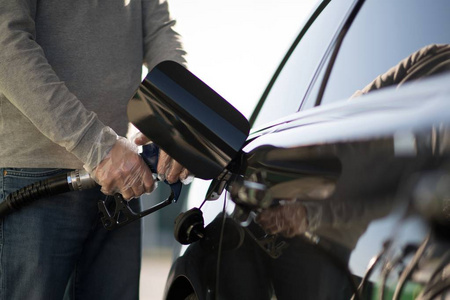 高加索司机用塑料手套给他的现代汽车加油。 加油站的概念。