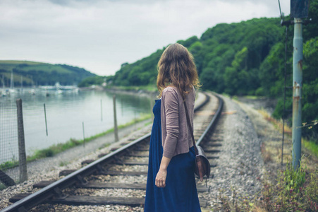 一位年轻女子正走在河边的铁轨旁