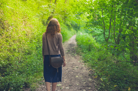 一个年轻的女人正在森林里散步