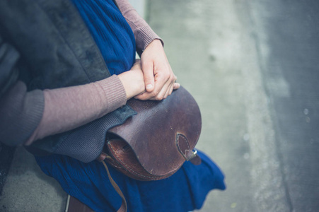 一位年轻女子在城外拿着一个手提包