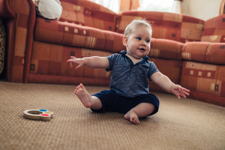 一个小婴儿正在客厅地板上玩拨浪鼓