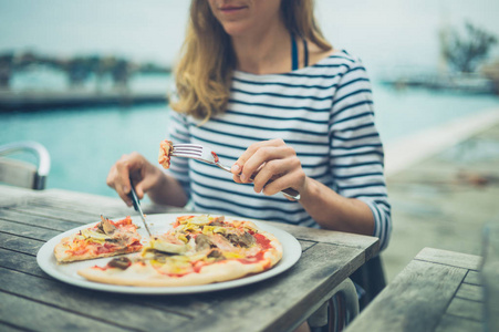 一个年轻的女人正在河边吃披萨