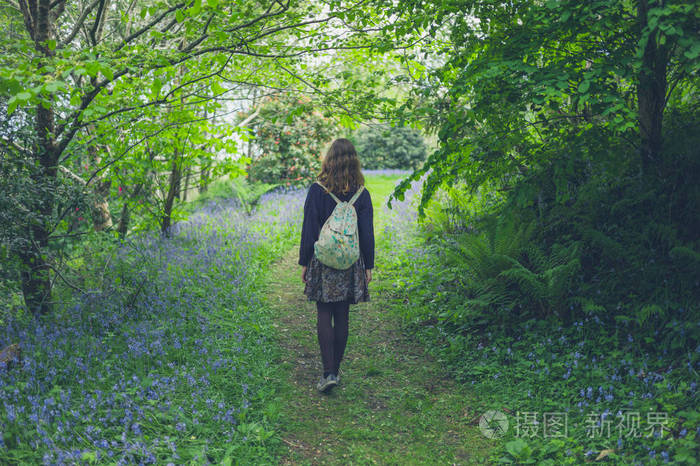 一个年轻的女人带着蓝铃在森林里散步