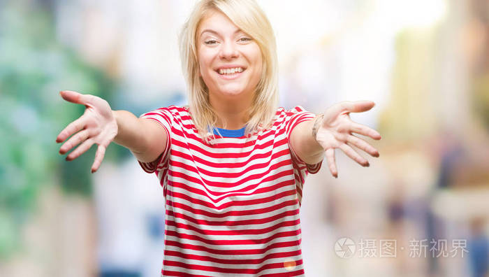 年轻漂亮的金发女人在孤立的背景下,看着相机,张开双臂拥抱微笑.