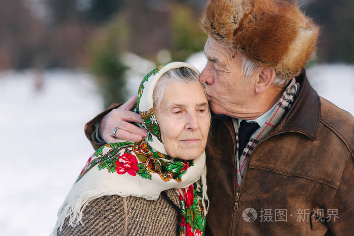 老夫妇的肖像.老人亲吻他的妻子在重量.