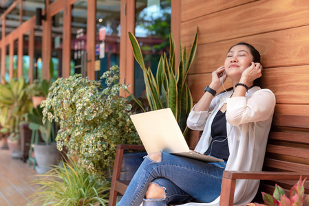 生活方式女性自由职业者喜欢听音乐和玩笔记本电脑户外工作空间在咖啡