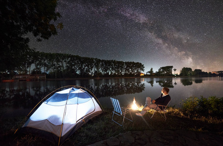 在篝火旁的湖岸上休息，欣赏美丽的夜空，满是星星和银河