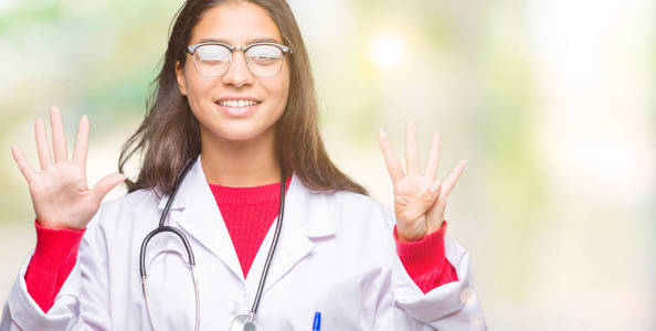 年轻的阿拉伯医生女人在孤立的背景上，用手指数字9，同时微笑，自信和快乐。