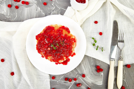 美国煎饼与果酱浆果振动蔓越莓灰色背景。 自制煎饼，加浆果酱和薄荷。 健康早餐，新鲜热煎饼和浆果酱。 上面的风景。