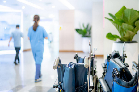 一组蓝色折叠轮椅，医生和护士在医院或医疗诊所的走廊上行走。 医疗及医疗服务概念