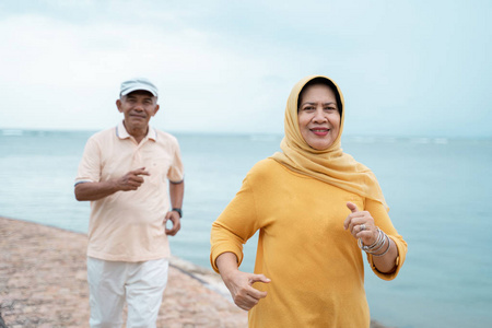 穆斯林老夫妇锻炼和在海滩上跑步