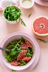 新鲜柑橘色拉，葡萄柚和芝麻在粉红色背景。 选择性聚焦。 生素春季排毒食物。