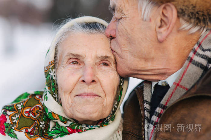 老夫妇的肖像。老人亲吻他的妻子在重量。冬天的时候, 老夫妇在公园里散步。幸福的家庭。黄金婚礼