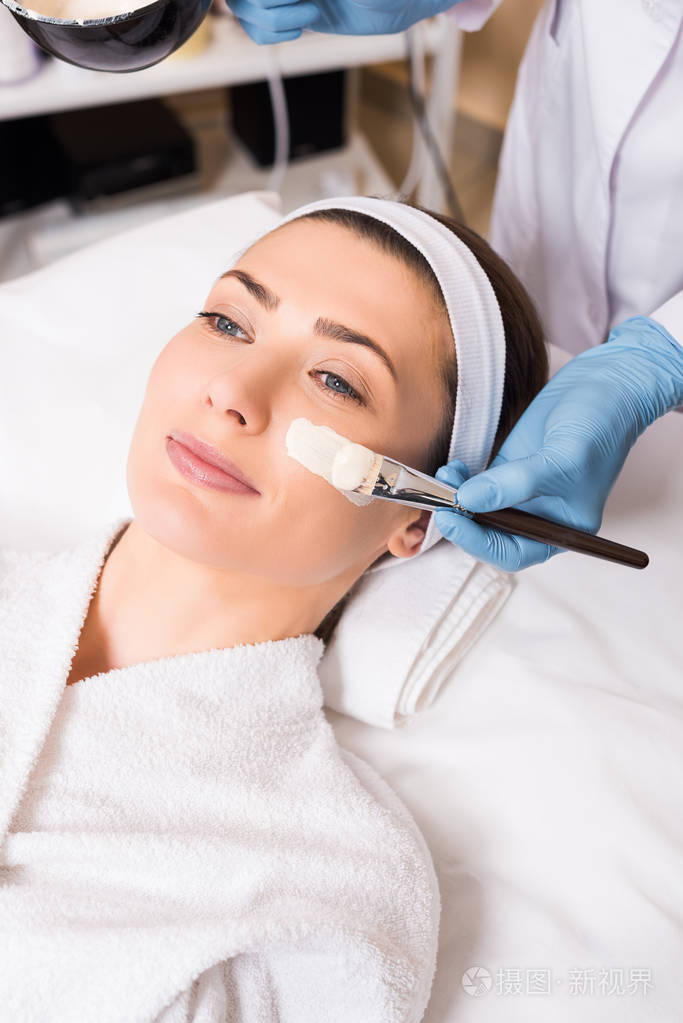 美容师开始在美容院用化妆刷涂抹脸美容面膜