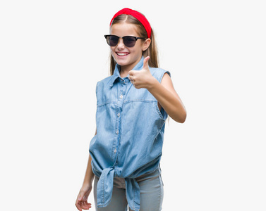 年轻漂亮的女孩戴着太阳镜在孤立的背景上，用手做快乐的拇指向上的手势。 赞许的表情看着相机，显示出成功。
