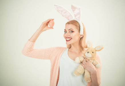 快乐的女人在兔子耳朵与玩具。兔子耳朵里的女人复活节快乐。春假。带着野兔玩具的女孩彩蛋。复活节彩蛋作为传统食物。感到兴奋