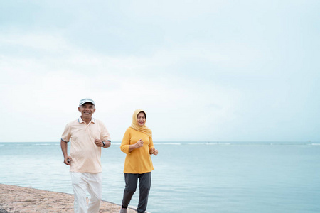 穆斯林老夫妇锻炼和在海滩上跑步