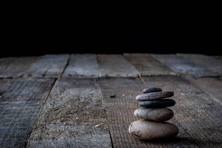木制桌子上的小圆石。 黑暗的背景。